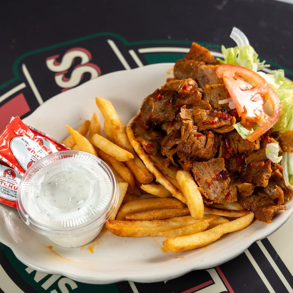Plate of seasoned döner meat, French fries, lettuce, tomato, and creamy dipping sauce.