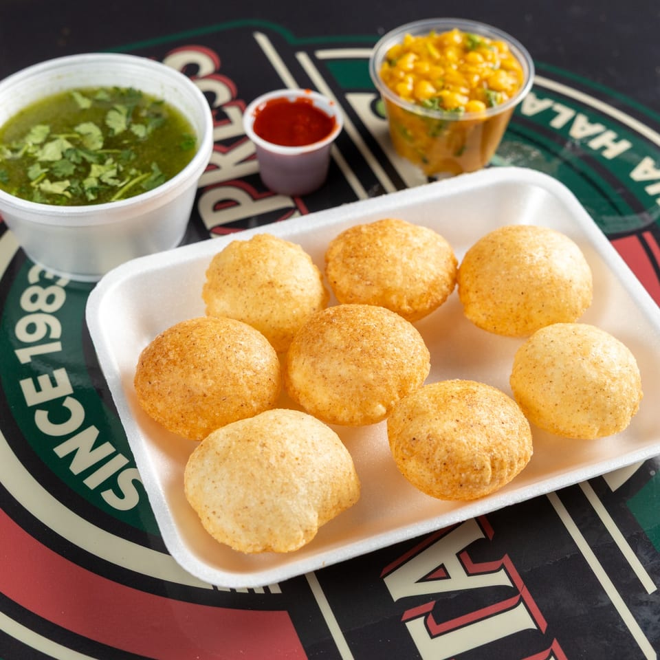 Pani puri shells served with fillings and sauces.