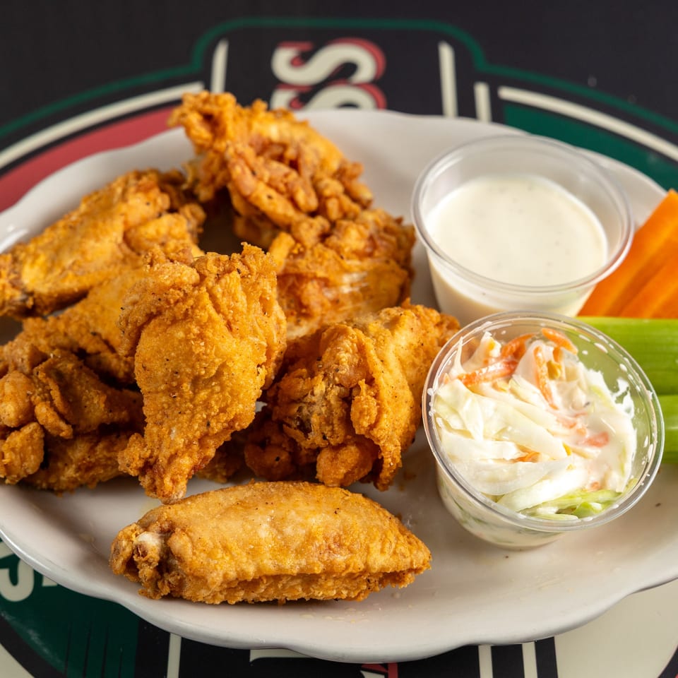 Crispy chicken wings with dipping sauce, coleslaw, carrots, and celery.